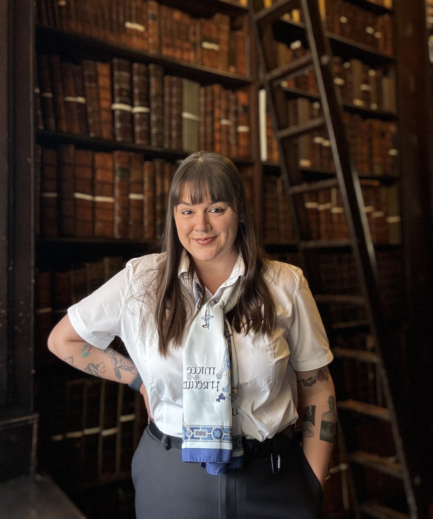 Library Guard Shauna in the Old Library wearing black trousers, a belt and white shirt