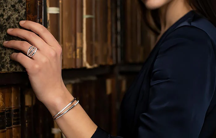 A woman wearing a black t shirt, with a silver ring and silver bracelet.